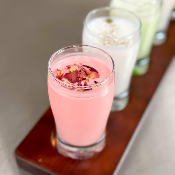 A row of colorful Indian lassi drinks, with a pink rose lassi in the foreground.